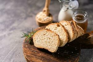 Artisan bread whole wheat baguette white milk and honey on rustic wooden board and abstract table. Sourdough bread photo