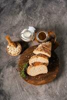 Artisan bread whole wheat baguette white milk and honey on rustic wooden board and abstract table. Sourdough bread photo