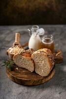 Artisan bread whole wheat baguette white milk and honey on rustic wooden board and abstract table. Sourdough bread photo