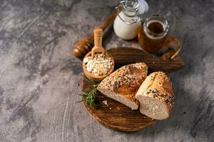 Artisan bread whole wheat baguette white milk and honey on rustic wooden board and abstract table. Sourdough bread photo