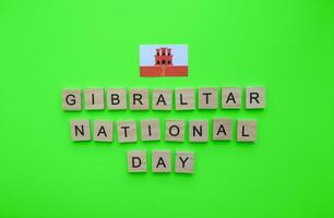 septiembre 10, Gibraltar nacional día, bandera de Gibraltar, minimalista bandera con de madera letras en un verde antecedentes foto