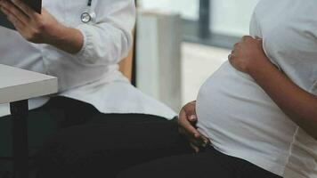 prenatal salud cuidado. cerca arriba de joven embarazada mujer visitando médico a prenatal clínica. médico ginecólogo examinar fetal latido del corazón Velocidad Moviente estetoscopio por desnudo bebé bache de expectante madre video