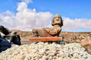 ancient statue of a man sitting on a rock photo