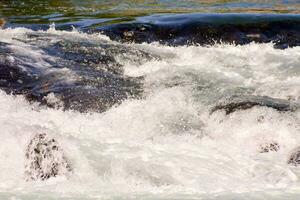 a close up of a river with water rushing over rocks photo