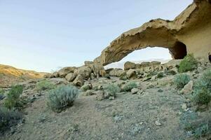 a rock arch in the desert photo