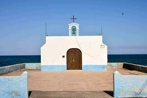 a small chapel on the beach with a cross above the door photo