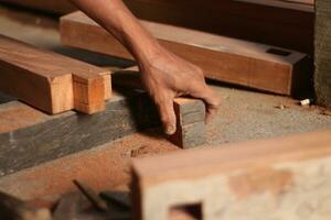 The hands of an Indonesian youth use their hands to make wood into house frames. photo