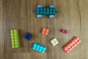 Top view of pieces plastic building blocks on wooden background photo