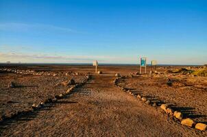 a dirt road in the middle of a desert with rocks and signs photo