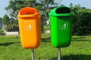 Orange and green trash bins in public park areas photo