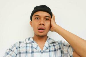 Surprise adult man wearing pajamas and beanie cap looking at camera. Isolated on a white background photo