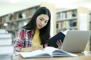 Young university student using laptop for online learning, searching and learning at library. photo