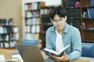 Young university student using laptop for online learning, searching and learning at library. photo