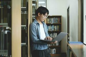 Young university student using laptop for online learning, searching and learning at library. photo