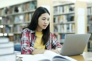 joven Universidad estudiante utilizando ordenador portátil para en línea aprendiendo, buscando y aprendizaje a biblioteca. foto