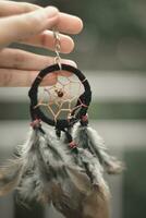 a hand holding on a dreamcatcher keychain photo