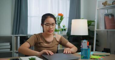 Tired young Asian woman working with a laptop on a desk photo