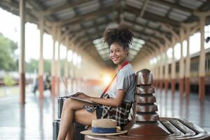 joven mujer niña hembra sentado utilizar computadora ordenador portátil y viaje bolso traje caso en el piso a estación foto