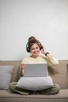 Portrait of Young Asian woman enjoy listening to music with headphones and using laptop, happy and relaxing time photo