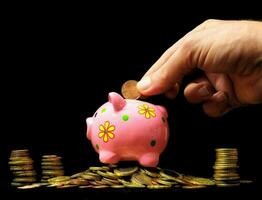 a hand putting coins into a piggy bank photo