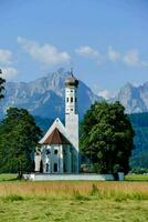 a church in the middle of a field with mountains in the background photo