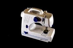 a white and blue sewing machine on a black background photo