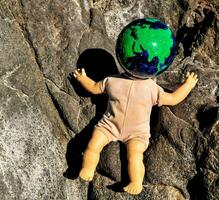 a baby doll with a globe on its head photo