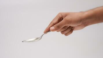 Male Hand Holding A Silver Stainless Spoon Closeup Photo Isolated On Grey Background