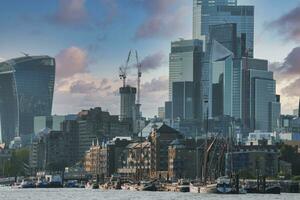 Boats moored at Thames riverbank with modern skyscrapers in background photo