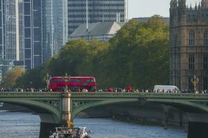 turistas caminando por excursión autobús en famoso Westminster puente hacia palacio foto