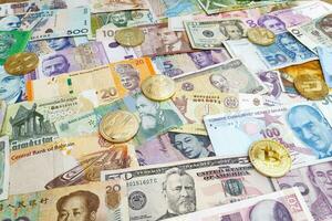 Cryptocurrency coins on top of a stack of international banknotes photo