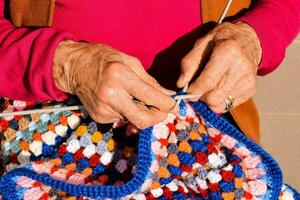 Woman is knitting a colorful crochet blanket photo