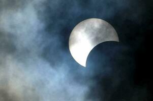 the moon during a partial solar eclipse in the sky photo