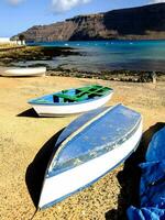 boats on the beach in front of a mountain photo