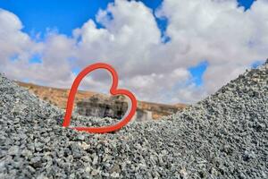 a red heart shaped object is sitting on top of a pile of gravel photo