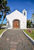 a white church with palm trees and a blue sky photo