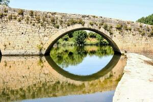 a stone bridge over a river with a reflection of the water photo