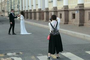 Sankt Petersburg Russia - 08 14 2023 Professional wedding photographer in the process of photographing with the newlyweds in nature. photo