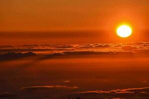 the sun is setting over the clouds as seen from the top of a mountain photo