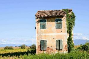 an old house in the middle of a field photo