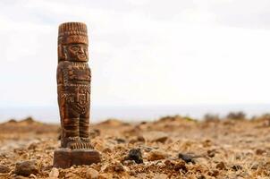 a wooden statue in the middle of a desert photo
