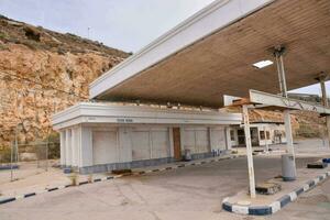 un gas estación con un grande rock pared detrás eso foto