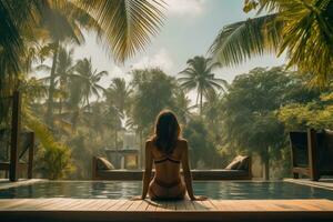 A woman wearing a hat looking at the water of a lagoon hotel and a swimming pool photo