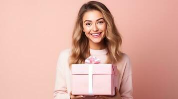 Beautiful girl standing on a pink background with a gift in the hands photo