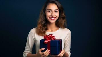 Beautiful girl standing on a blue background with a gift in the han photo