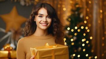 hermosa niña en pie en un dorado antecedentes con un regalo en el manos foto