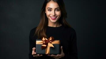 hermosa niña en pie en un negro antecedentes con un regalo en el manos foto