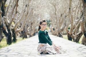 Portrait of asian women sitting inside the Plumeria tunnel in front of Nan national museum of Nan province of Thailand. photo