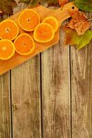 collection beautiful colorful autumn leaves and orange slices on wooden background. photo