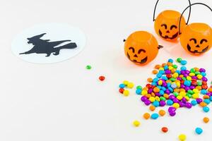 Halloween, pumpkins, witch silhouette flying on broomstick, full moon, colored sprinkles, on white background. Selective focus. photo